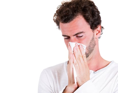 Closeup portrait of sick, ill young man, student, worker with allergy, germs cold, blowing his nose with kleenex, looking miserable, unwell, very sick isolated on white background. Flu season, vaccine