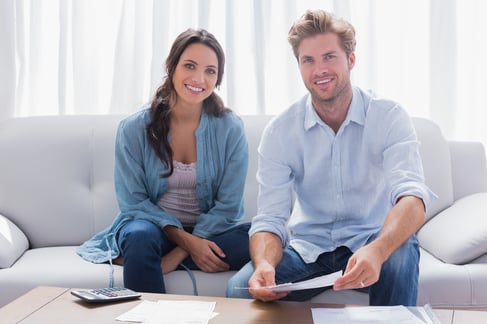 Happy couple doing their accounts sat in a couch